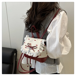 Detail of red and cream mini backpack with lace edges and heart charm on model