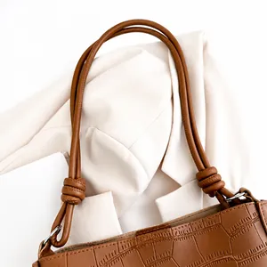 Dettaglio borsa tote marrone in pelle coccodrillo con manici cilindrici annodati