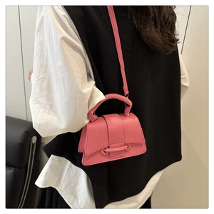 Detail of pink mini trapezoid crossbody bag with lychee texture and round handle on model