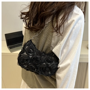 Detail of black shoulder bag featuring 3D organza roses and a silver metal chain strap