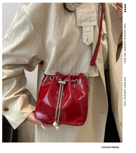 Detail of red patent leather bucket bag with silver chain drawstrings and pearl charms