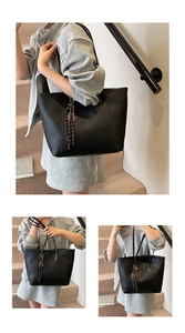 Detail of black large-capacity tote bag in lychee leather with woven tassel charm