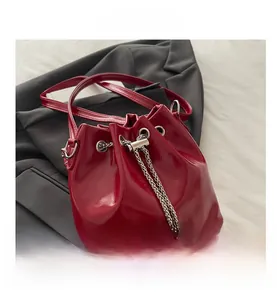 Detail of red glossy bucket bag with silver chain drawstring and metallic beads