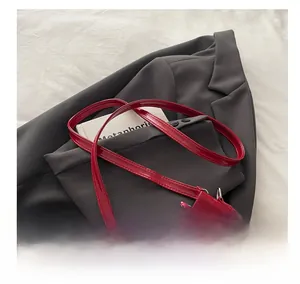 Detail of red patent leather bucket bag showing comfortable shoulder strap and chain