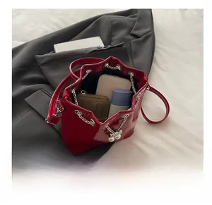 Detail view of red glossy leather bucket bag showing large capacity for essentials