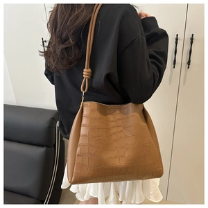 Borsa tote marrone motivo coccodrillo con tracolla annodata indossata da una modella