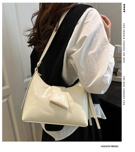 Detail view of cream glossy leather hobo bag with unique geometric layering and thin strap
