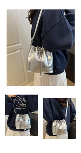 Detail of silver bucket bag featuring metallic texture, drawstring, and pearl chain