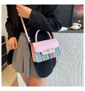 Detail of a pink leather crossbody bag with colorful woven base on a female model