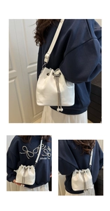 Three-angle view of white glossy bucket bag with pearl chain and drawstring closure