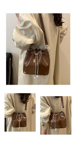 Detail of brown glossy bucket bag featuring silver chains and elegant pearl accents