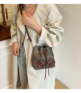 Détail du sac seau en toile avec finitions en cuir, cordon de serrage et œillets métalliques