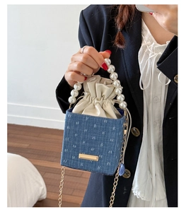 Close-up of denim bucket bag with pearl handle and jacquard pattern on blue fabric