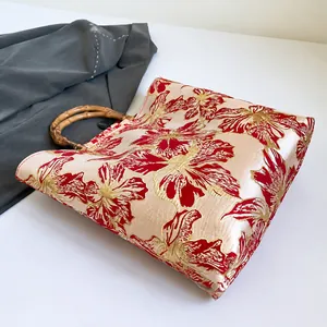 Detail showing the intricate floral embroidery and authentic bamboo handles of the tote bag