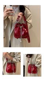 Detailed view of red bucket bag with silver chain drawstring and oversized white pearls
