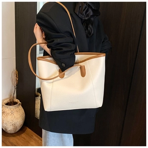 Dettaglio della borsa tote crema minimalista con bordo marrone e ampia capienza indossata