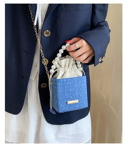Detail of denim bucket bag with pearl handle and polka dot embroidery on model