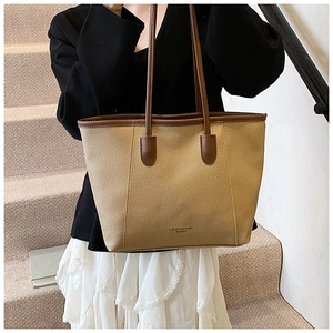 Dettaglio della trama in pelle kaki della borsa tote con manico marrone su scale in pietra