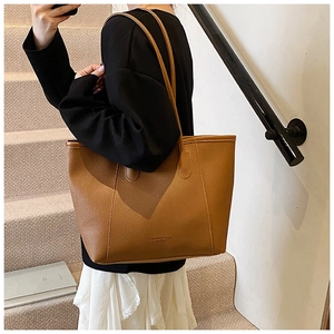 Detail of caramel brown tote bag showing lychee leather texture and long straps