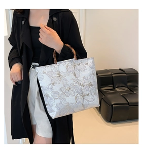 Detail of silver jacquard tote bag with floral pattern and natural bamboo handle