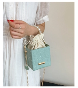Detail of mint green textured box bag with pearl handle and golden chain strap