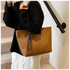Bolso tote de cuero marrón con colgante de raqueta de tenis y detalle de texto en relieve