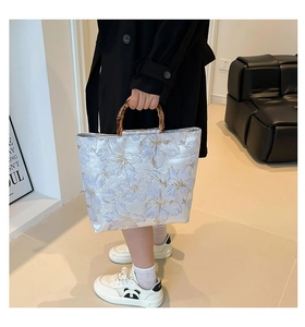 Detail of vintage jacquard tote bag featuring bamboo handle and floral silk texture