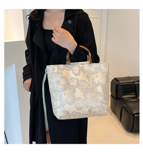 Detailed close-up of a floral jacquard tote bag with elegant bamboo top handles on black coat