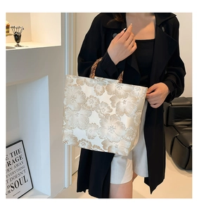 Detailed view of jacquard floral patterns and bamboo handle on the champagne tote bag