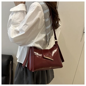 Detail view of burgundy leather shoulder bag with a gold streamlined metal buckle