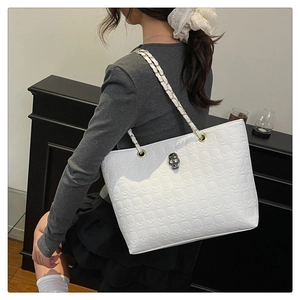 Detailopname van de witte shopper met schedelreliëf en gesp met strassteentjes
