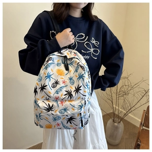 Close-up of a tropical print backpack with palm trees and flowers worn by a model