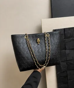 Close-up of black tote bag featuring skull embossed pattern and silver skull charm detail