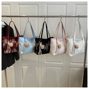 Detail van kleurrijke tote bags met reliëftextuur en schattige pluche beerhangers