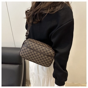 Detail shot of brown monogram crossbody bag with adjustable strap worn on the shoulder