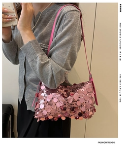 Close-up of pink sequined shoulder bag with metallic reflection on a knit cardigan