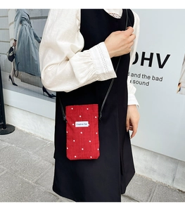 Détail d'un mini sac de téléphone rouge avec broderie florale et fine bandoulière noire