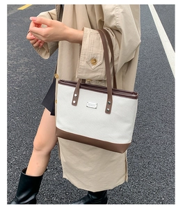 Détail du sac cabas en toile avec coutures en cuir marron et plaque logo en métal