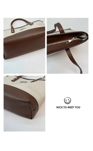 Détail du sac cabas en toile avec garniture en cuir marron, fermeture éclair et coutures