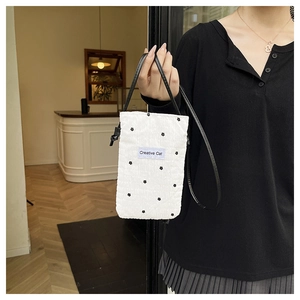 Détail du petit sac blanc en tissu froissé à fleurs noires avec bandoulière fine