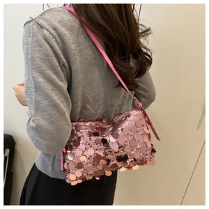 Close-up of pink sequin shoulder bag with detailed texture and slim strap shown on model