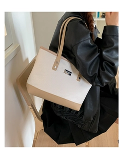 Gros plan du sac cabas tissé avec finitions en cuir kaki et plaque logo argentée