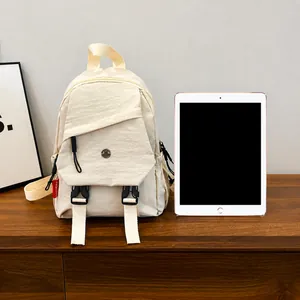Detail van gebroken witte mini-rugzak met zwarte gespen vergeleken met een tablet
