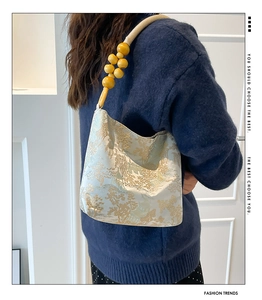 Détail du sac à bandoulière en jacquard bleu clair avec broderies d'or et perles en bois