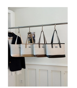 Détail de cabas tissés multicolores en beige et marron suspendus sur un portant