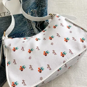Detalle del bolso de lona floral con letras Beautiful y accesorios en color dorado