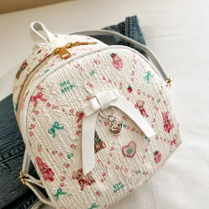 Close-up of white backpack with pink rabbit prints and heart metal pendant detail