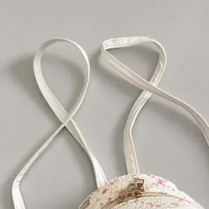 Detail of slim white faux leather shoulder straps with fine stitching on floral backpack