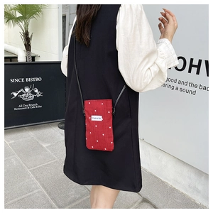 Sac bandoulière pour téléphone à fleurs rouges porté par une personne en plein air