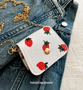 Détail du mini sac bandoulière blanc avec imprimé fraise et chaîne dorée élégante